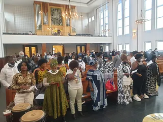 Große Gruppe von Menschen in festlicher Kleidung steht in einer Kirche.