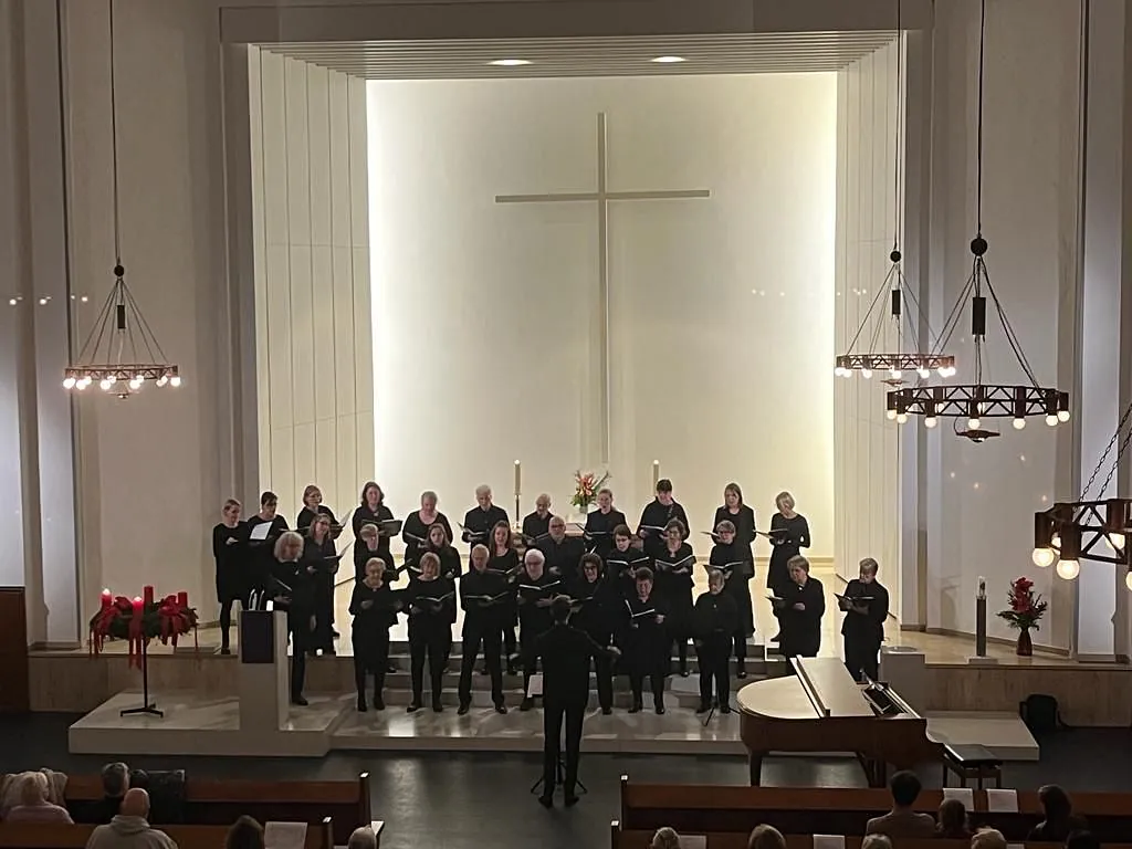 Chor singt vor Altar und großem Kreuz in einem Kirchenraum.