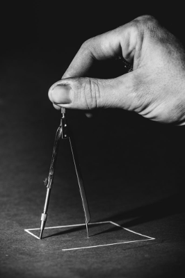 Hand zeichnet mit Zirkel.