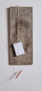  Klemmbrett mit Notizblock und Bleistift hängen an einer Schnur an einem Holzbrett.