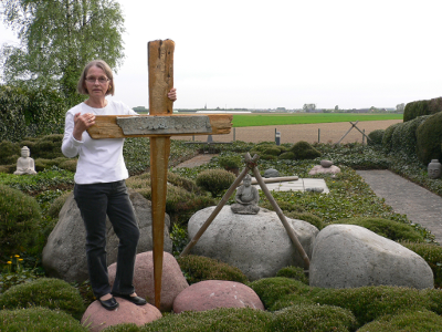 Eine Frau steht in einem Garten mit einem großen Holzkreuz.