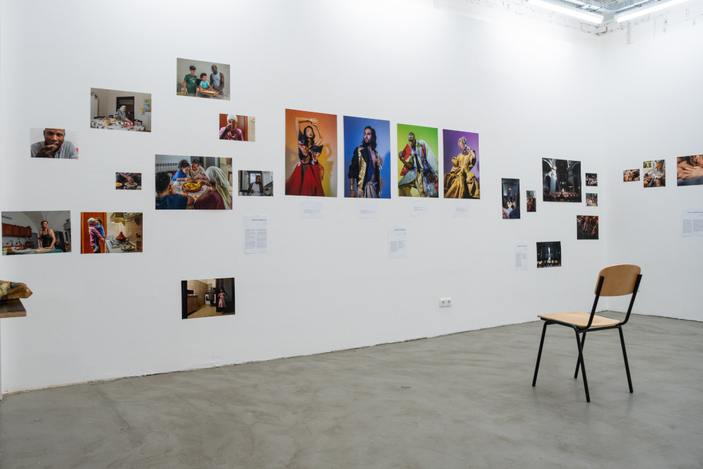 Kunstraum mit verschiedenen Fotos an einer weißen Wand und einem Stuhl.