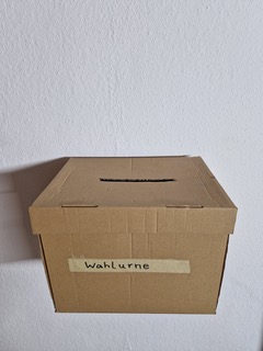 Brauner Karton mit der Aufschrift „Wahlurne“ (Wahlurne).