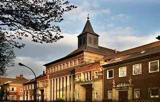Historische Backsteinkirche mit Turm, umgeben von Gebäuden und Bäumen.