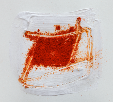 Abstraktes Gemälde mit rotem Pulver auf weißer Farbe.