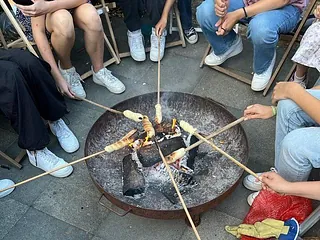 Menschen grillen Stockbrot über einem Feuer.