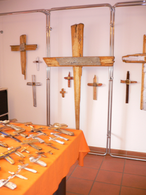 Ein Raum mit verschiedenen Kreuzen an der Wand und auf einem orangefarbenen Tisch.