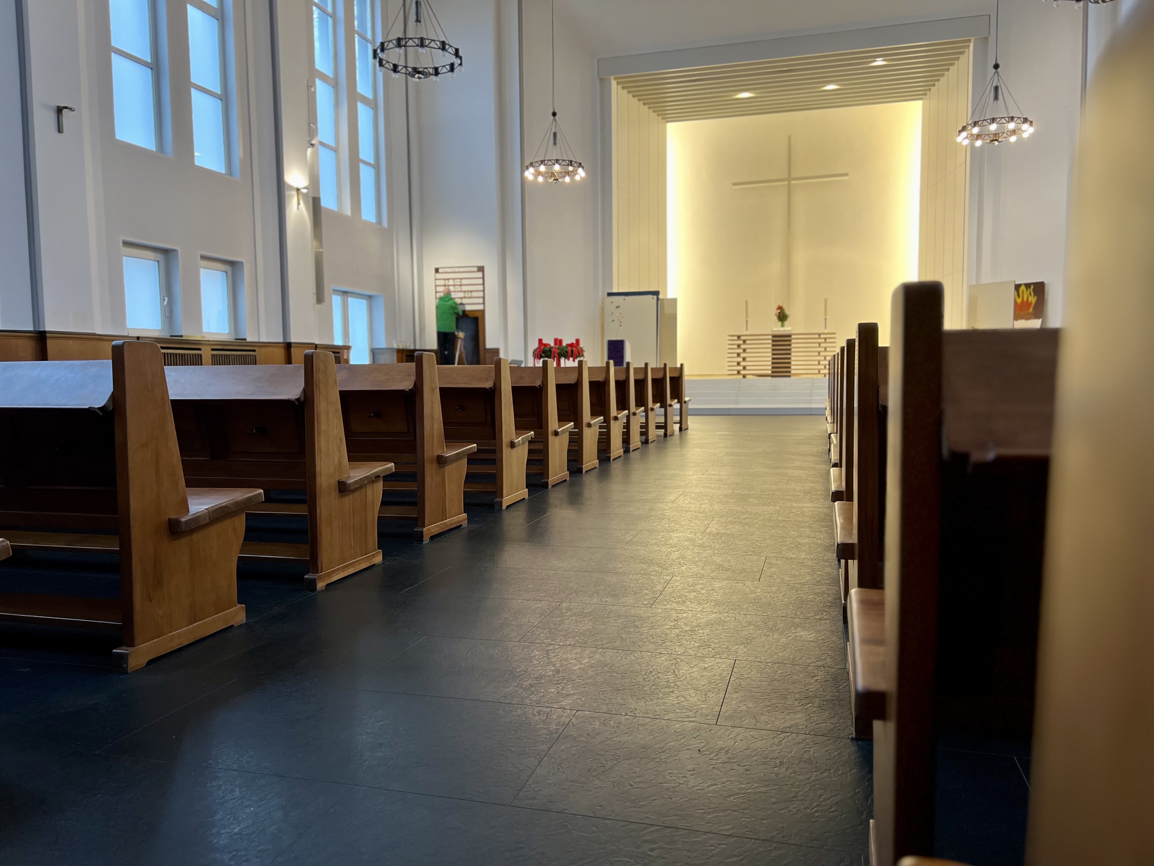 Reihen von leeren Holzbänken in einer hellen Kirche.