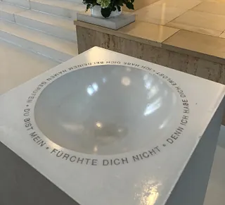 Metallene Taufschale mit Inschrift und Spiegelung.