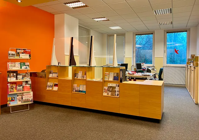 Empfangsbereich mit Holztheke, Informationsständern und Büros.