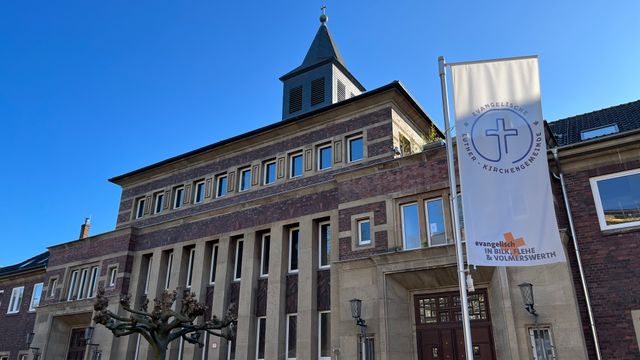 Historisches Backsteingebäude mit Flaggen und blauem Himmel.
