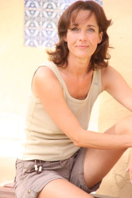 Porträt einer lächelnden Frau in beigefarbenem Top und Shorts, die nach unten schaut.