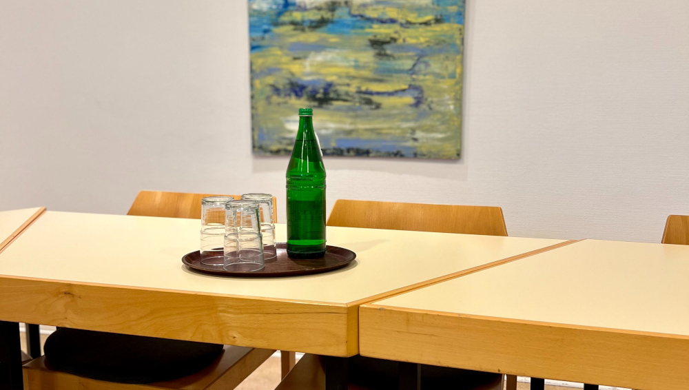 Eine grüne Flasche und Gläser auf einem Tablett auf einem Tisch mit einem Bild im Hintergrund.